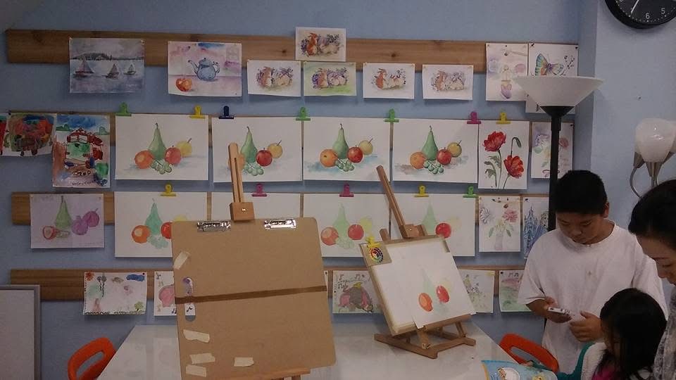 Students painting in a classroom with artwork displayed on the wall