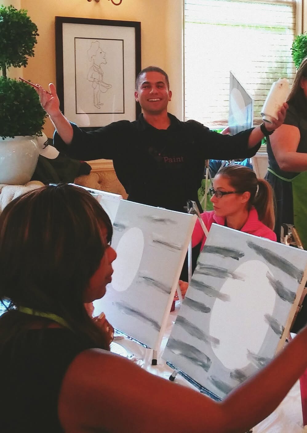 Carlos teaching a group while participants work at their easels